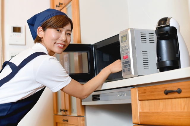 笑顔でキッチンオーブンの庫内を掃除する女性